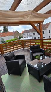 a wooden deck with chairs and tables and a large umbrella at Ferienwohnung Regina in Undenheim