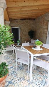 a patio with a wooden table and white chairs at Casa mirador Tía Amalia in San Mamede de Carnota