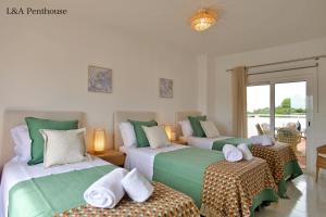 una camera da letto con due letti con lenzuola verdi e bianche di Penthouse L&A Prainha with sea view, 2 Terraces ad Alvor Altre 70 foto