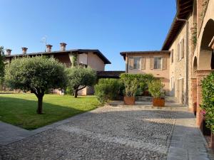 ein Innenhof eines Hauses mit Bäumen und Gras in der Unterkunft La Maison in Franciacorta in Colombaro