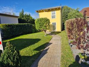 een tuin met een geel huis en een stoep bij Ferienhaus an der Brunnenaue 4 Sterne, E-Ladestation am Haus, Wlan, Netflix, Garten in Sagard