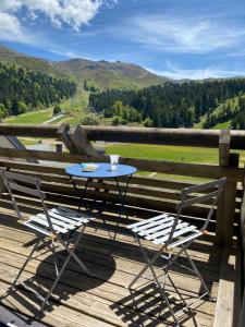 a table and two chairs on a deck with a view at Super Lioran T2 dernier étage in Laveissière +3 photos