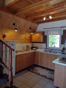 a kitchen with wooden cabinets and a sink and a window at Domki pod Skałką in Baligród