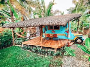 a small house with a thatched roof and a wooden deck at Jeepney Siargao in General Luna