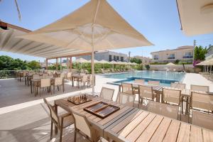 an outdoor patio with tables and chairs and a pool at Kamer Exclusive Hotel & Suites in Çeşme