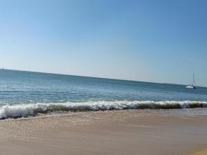 a beach with the ocean and a boat in the water at Le Souffle Marin in Mesquer