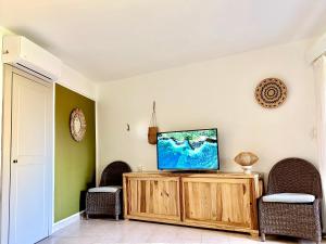 a living room with two chairs and a television on a cabinet at #Vacances en #Martinique in Sainte-Anne