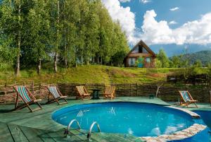 a pool with chairs and a house in the background at Ethno village Montenegro Brezna in Plužine