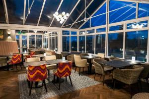 a restaurant with tables and chairs and large windows at Lyons Woodlands Hall in Ruthin