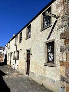 a white brick building with windows on a street at Rose Wynd Cottage-Close to beach in Crail