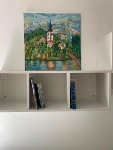 a painting of a church on a shelf with books at At the Burkulis' in Ljubljana