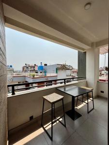 a table and stool on a balcony with a large window at Lavish Stay at Boudha, Kathmandu, Heuju Residence in Kathmandu