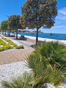 a walkway next to the water with trees and plants at Apartments Leona in Umag