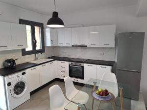 a kitchen with white cabinets and a table and chairs at Terracotta Sunset Naxos in Galanádhon