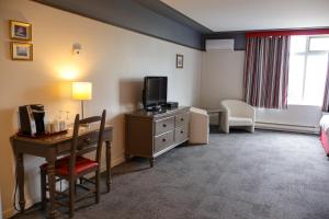 a hotel room with a desk and a tv at Hôtel au Petit Berger in La Malbaie