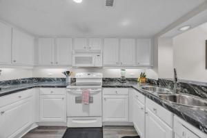 a white kitchen with white cabinets and a sink at Oceanfront Condo Huge Pools Top Rated Ocean Creek Resort in Myrtle Beach +42 photos