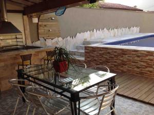 un tavolo in vetro e sedie accanto alla piscina di Casa com piscina privativa a Bertioga