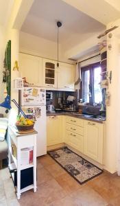 a kitchen with white cabinets and a table with a bowl of fruit at Peace&love-sea studio in Poros
