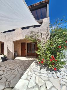 a house with a stone courtyard with red flowers at Appartement Rez de Villa Terrasse Piscine Parking privé in Hyères