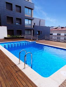 a large blue swimming pool in front of a building at Ático Chill-Out de lujo con piscina y garaje gratis in Vigo