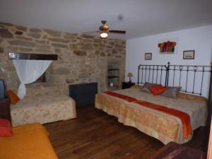 La Posada de Pedrazales في Pedrazales: غرفة نوم بسريرين وجدار حجري