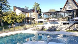 a house with a swimming pool with chairs and umbrellas at El Nogal Apart Hotel in Villa General Belgrano