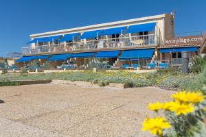 a building with blue balconies and flowers in front of it at Le Surplage in Hyères