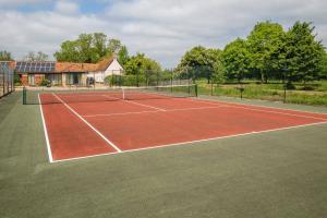un court de tennis devant une maison dans l'établissement East Green Farm Cottages - The Granary, à Saxmundham