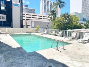 a swimming pool with lounge chairs and buildings at Free parking Comfy central Waikiki in Honolulu