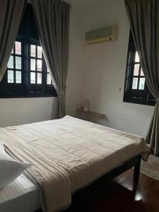 a bed in a bedroom with two windows at MIA guests house in Nilai