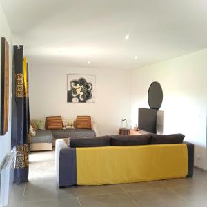 a living room with a couch and a yellow couch at La villa des Mûriers très spacieuse de 1 à 8 voyageurs avec lit bb dans un environnement calme dans les coteaux in Malause