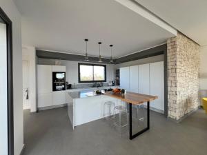 an open kitchen with white cabinets and a wooden table at Exceptional villa Essaouira in Ghazoua
