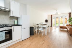 a kitchen and living room with a table and chairs at Sleek and Stylish 2BD Home with a Garden Anerley in London +10 photos