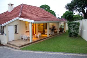 a small white house with a patio and a yard at Coweys Corner in Durban