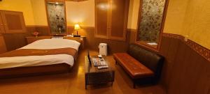 a hotel room with a bed and a bench and a table at ホテル　ネグレスコ in Amagasaki