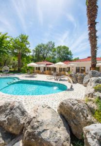 a swimming pool with rocks in front of a house at VODİNA LOUNGE SUİTEs in Kayakoy