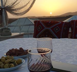 a table with a glass vase and a plate of food at Sunshine luxury desert camp in Merzouga