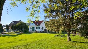 a white house with a tree in a yard at Zöld Vendégház - Siklós in Siklós