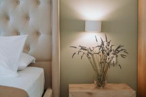 a vase of flowers on a table next to a bed at Sivota Seafront Studios in Sivota