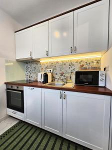 a kitchen with white cabinets and a sink and a microwave at Zöld Vendégház - Siklós in Siklós
