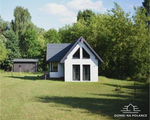 a small white house in the middle of a yard at Domki na polance in Horyniec