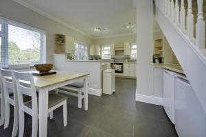 a white kitchen with a table and chairs and a staircase at Super 5 Bedroom Family Friendly Retreat Rustington in Littlehampton +17 photos
