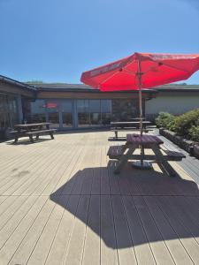a picnic table with an umbrella on a patio at SADDLERS RETREAT 9, driftwood Close in Llwyngwril