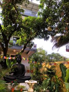 a statue in a garden with a tree and a building at Arambol Bliss Hotel Apartments in Arambol