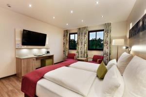 a hotel room with two beds and a flat screen tv at Weingut Sandwiese Winzerhotel in Worms
