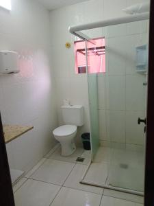 a bathroom with a toilet and a glass shower at Suíte Praia Grande in Arraial do Cabo