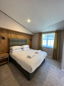 a bedroom with a large bed with white sheets at Sandy Lane 18 - Lodge with Hot Tub in Allerthorpe