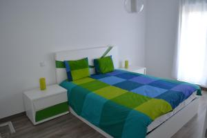 a colorful bed in a white room with a window at Casa Perola De Prata in Famalicão +10 photos