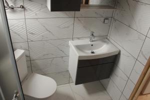 a white bathroom with a sink and a toilet at Domki u Rybaka Wapnica in Wapnica +48 photos
