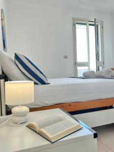een slaapkamer met een bed en een tafel met een boek bij Holiday salento in Leuca